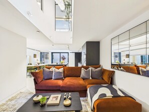 A modern living room with a sectional sofa, a coffee table, and a large mirror. - Spacious London Bridge Townhouse with Roof Terrace (Greater London)