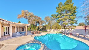 Un patio trasero con piscina, mobiliario exterior y una pérgola.