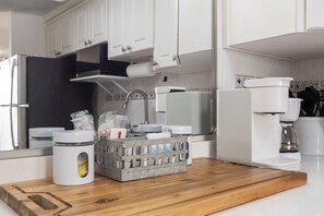 Eine Küche mit weißen Schränken, einem Edelstahlkühlschrank, einer Kaffeemaschine und einer Obstschale auf der Arbeitsfläche.