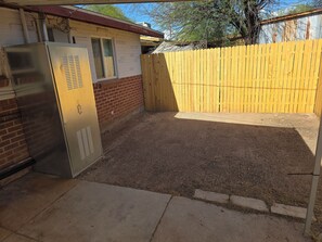 A fenced backyard with a metal utility box, a brick wall, and a wooden fence.