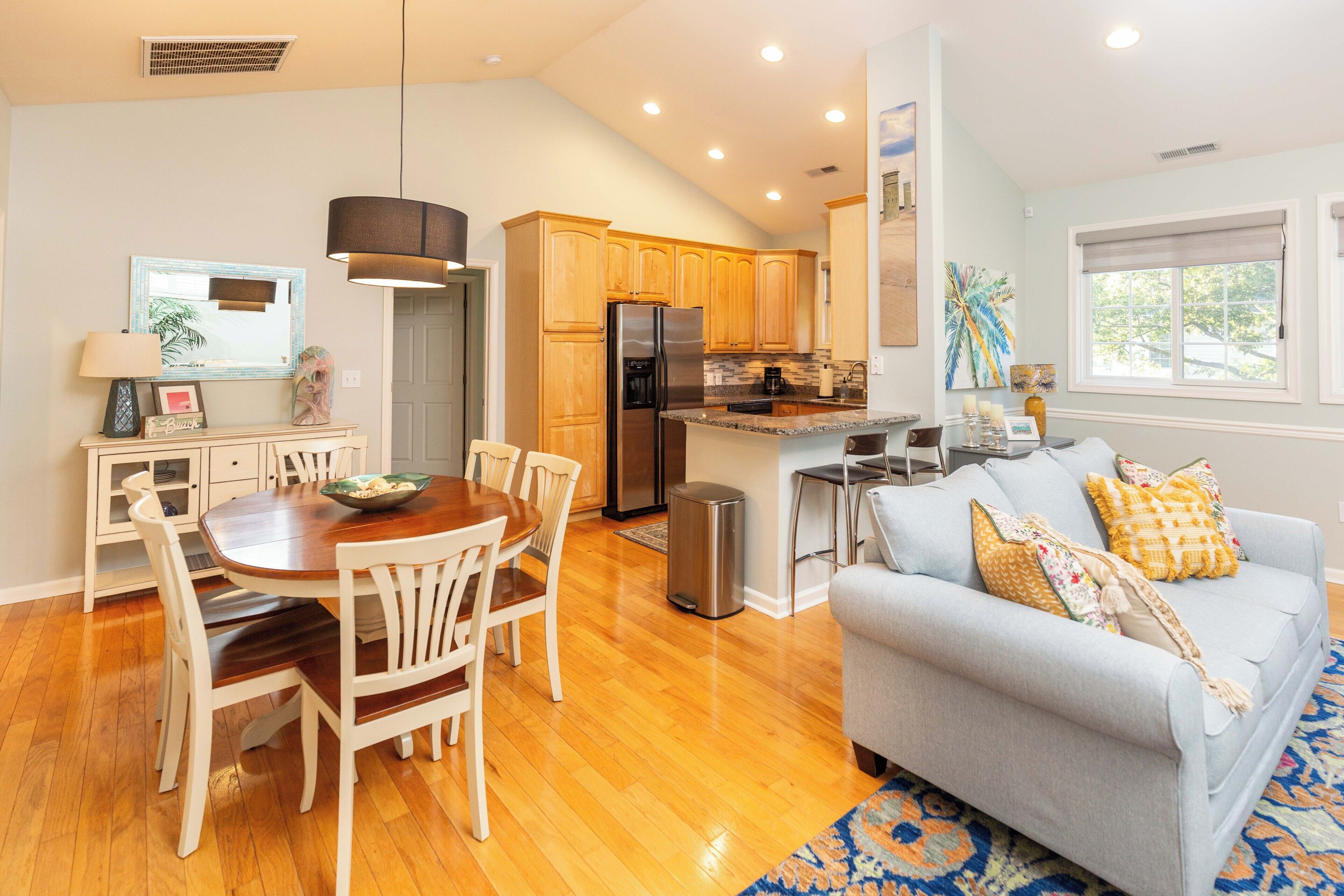 Una cocina moderna con armarios de madera, un refrigerador de acero inoxidable y una zona de comedor con mesa y sillas de madera.