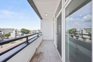 A balcony with a view of a residential street, a railing, and a door leading to an interior space. - Brand New 2 Bedrooms 2 Full Baths Condo! (Seaside heights)