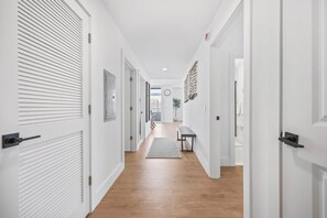 A hallway with white doors, a bench, and a rug. - Brand New 2 Bedrooms 2 Full Baths Condo! (Seaside heights)