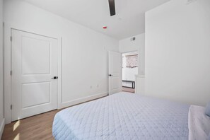 A bedroom with a bed, two doors, a closet, and a wall-mounted coat rack. - Brand New 2 Bedrooms 2 Full Baths Condo! (Seaside heights)