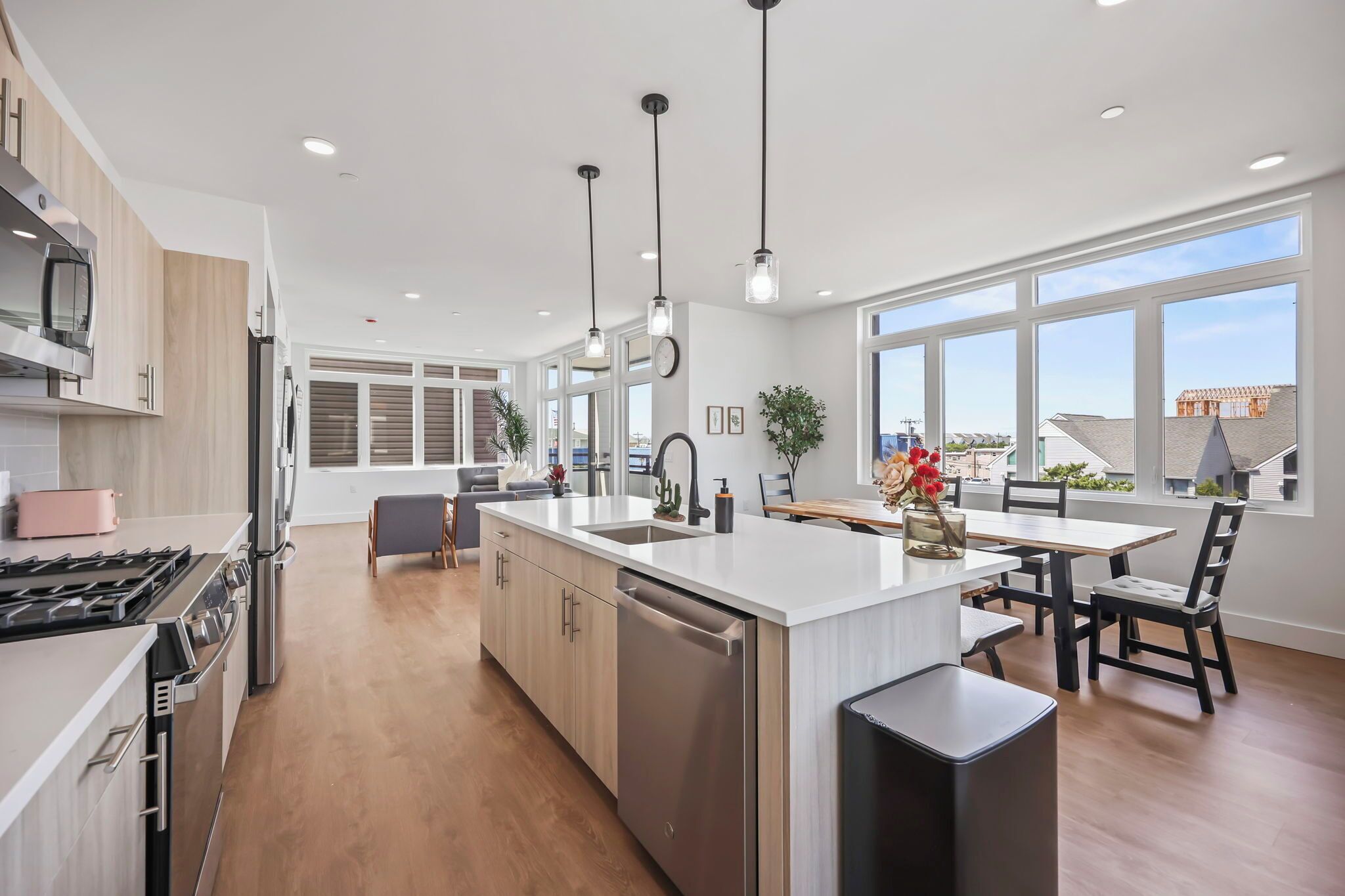 A modern kitchen with a central island, stainless steel appliances, and large windows.