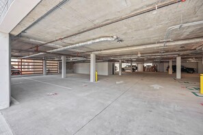 A multi-level parking garage with concrete floors and columns, ventilation ducts, and a few parked vehicles. - Brand New 2 Bedrooms 2 Full Baths Condo! (Seaside heights)