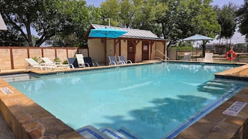 A swimming pool with lounge chairs and a small building with a blue roof.