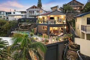 A multi-level residential building with a balcony, outdoor seating, and a pool. - Beachfront Apartment w/Ocean Views & BBQ (North Curl Curl)