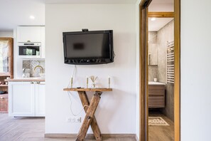 A modern kitchen with a flat-screen TV mounted on the wall, a wooden stand with candles, and a visible power outlet. - Le Flocon - Petfriendly - Proche pistes (Hauteluce)