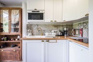 A kitchen with white cabinets, a microwave, a sink with a gold faucet, and a coffee maker. - Le Flocon - Petfriendly - Proche pistes (Hauteluce)