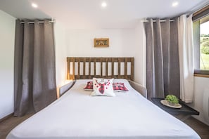 A bedroom with a wooden headboard, a bed with white bedding, two pillows, a small bedside table with a plant, and curtains on the windows. - Le Flocon - Petfriendly - Proche pistes (Hauteluce)