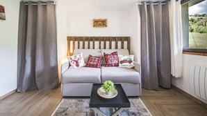 A modern living room with a sofa, decorative pillows, a small table with a plant, and a window with curtains. - Le Flocon - Petfriendly - Proche pistes (Hauteluce)