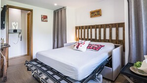 A hotel room with a bed, a headboard, a bedside table, a wall-mounted clock, and a door. - Le Flocon - Petfriendly - Proche pistes (Hauteluce)