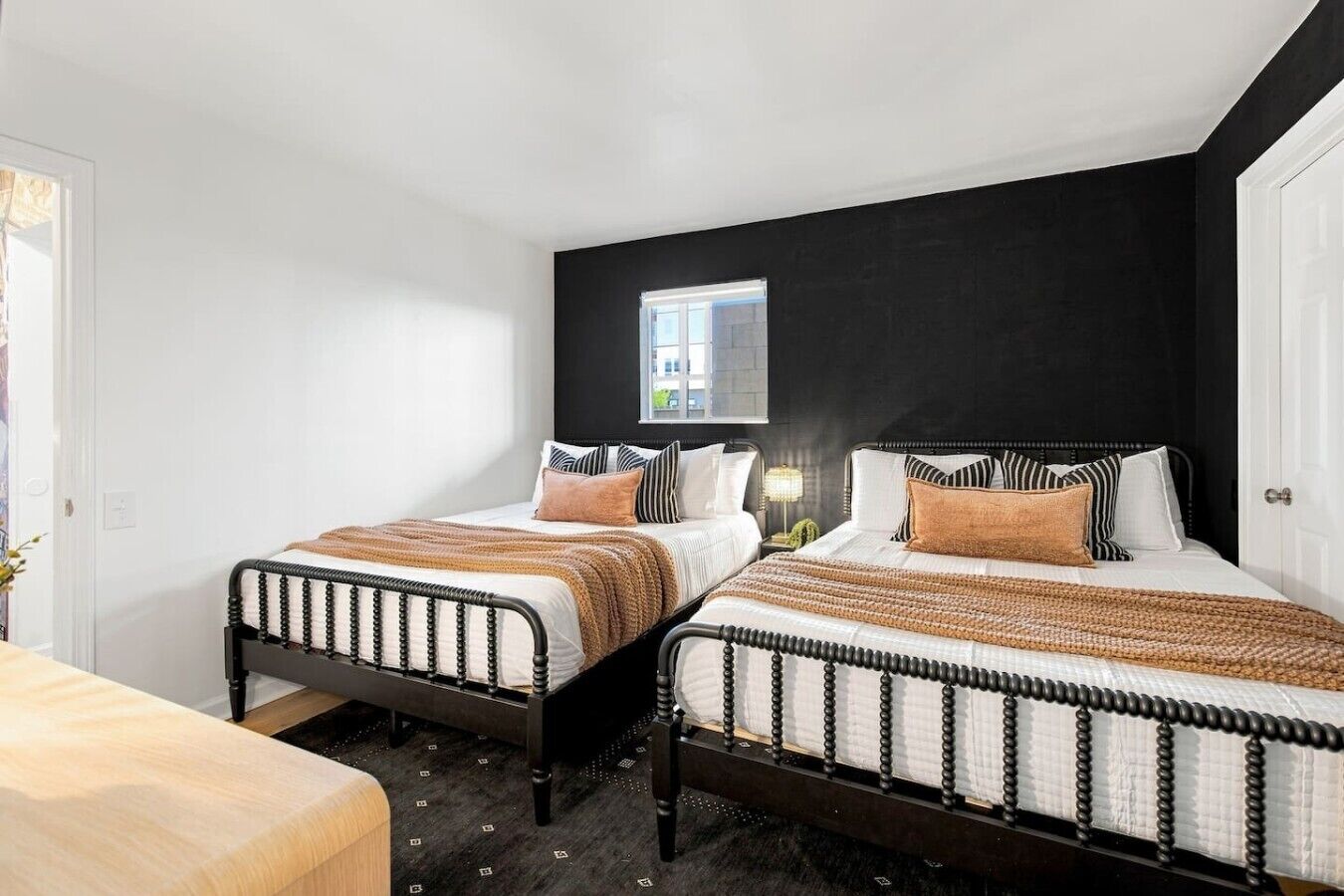 Een slaapkamer met twee bedden, een raam en een nachtkastje met een lamp.