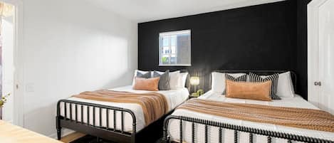 Een slaapkamer met twee bedden, een raam en een nachtkastje met een lamp.