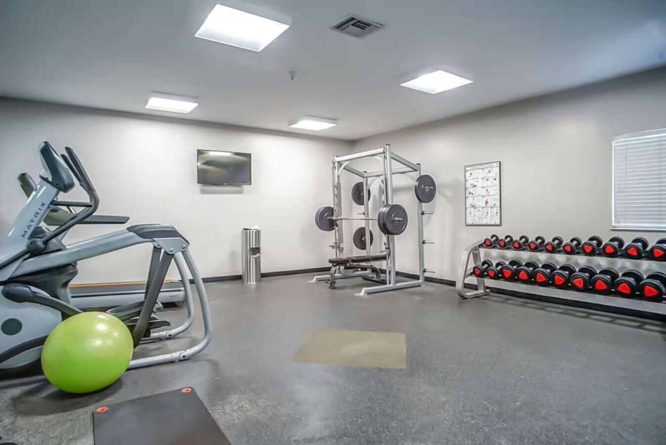 Ett gym med konditionsmaskiner, styrketräningsstationer och hantlar.
