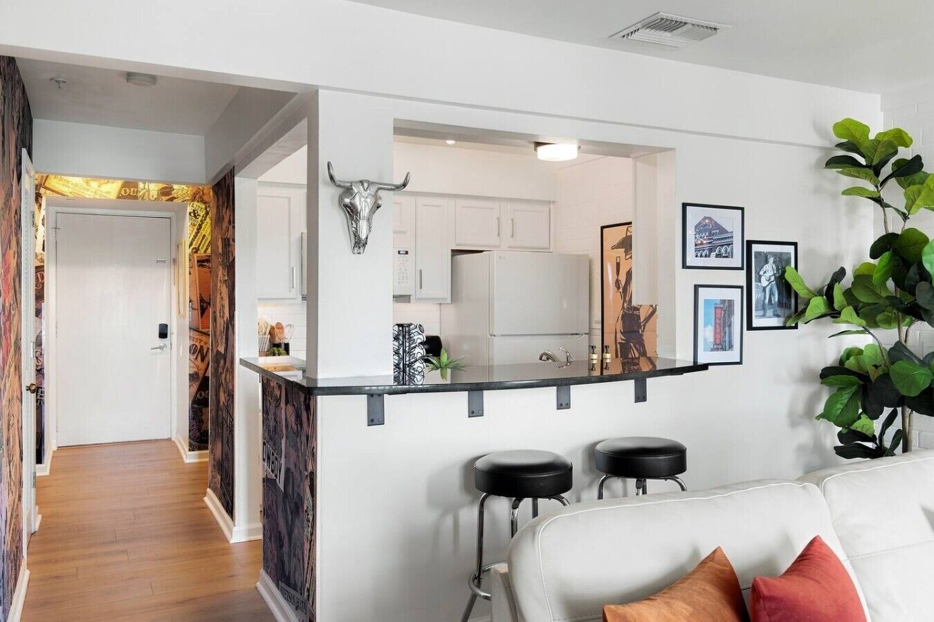 A modern kitchen with a bull skull decoration, a white countertop, and a bar area with stools.