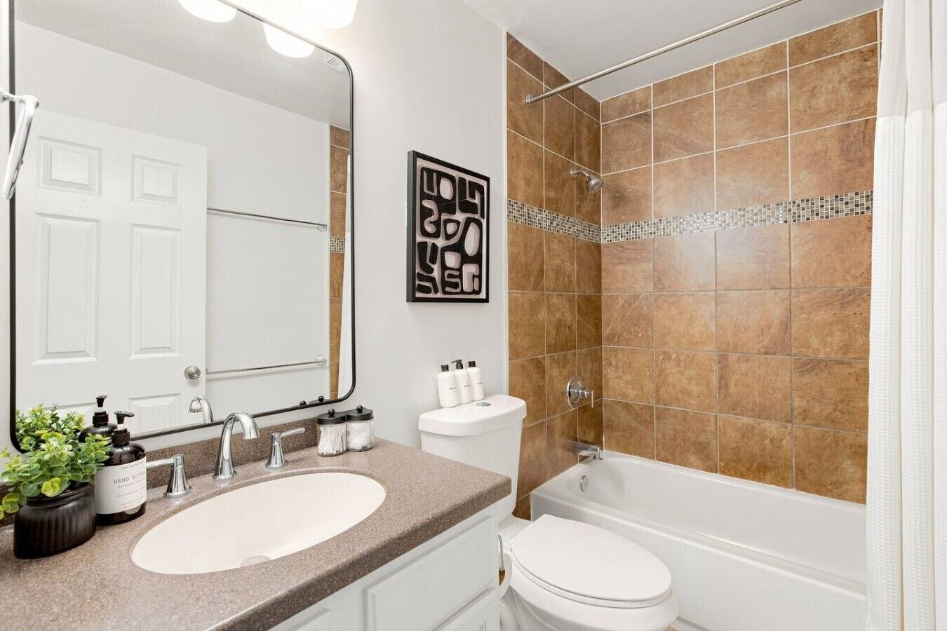Une salle de bain équipée d’un lavabo, d’un miroir, de toilettes et d’un espace douche.