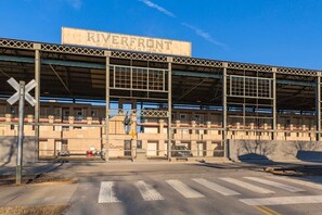 A building with a sign reading 'RIVERFRONT CONDOMINIUMS' and a railroad crossing.