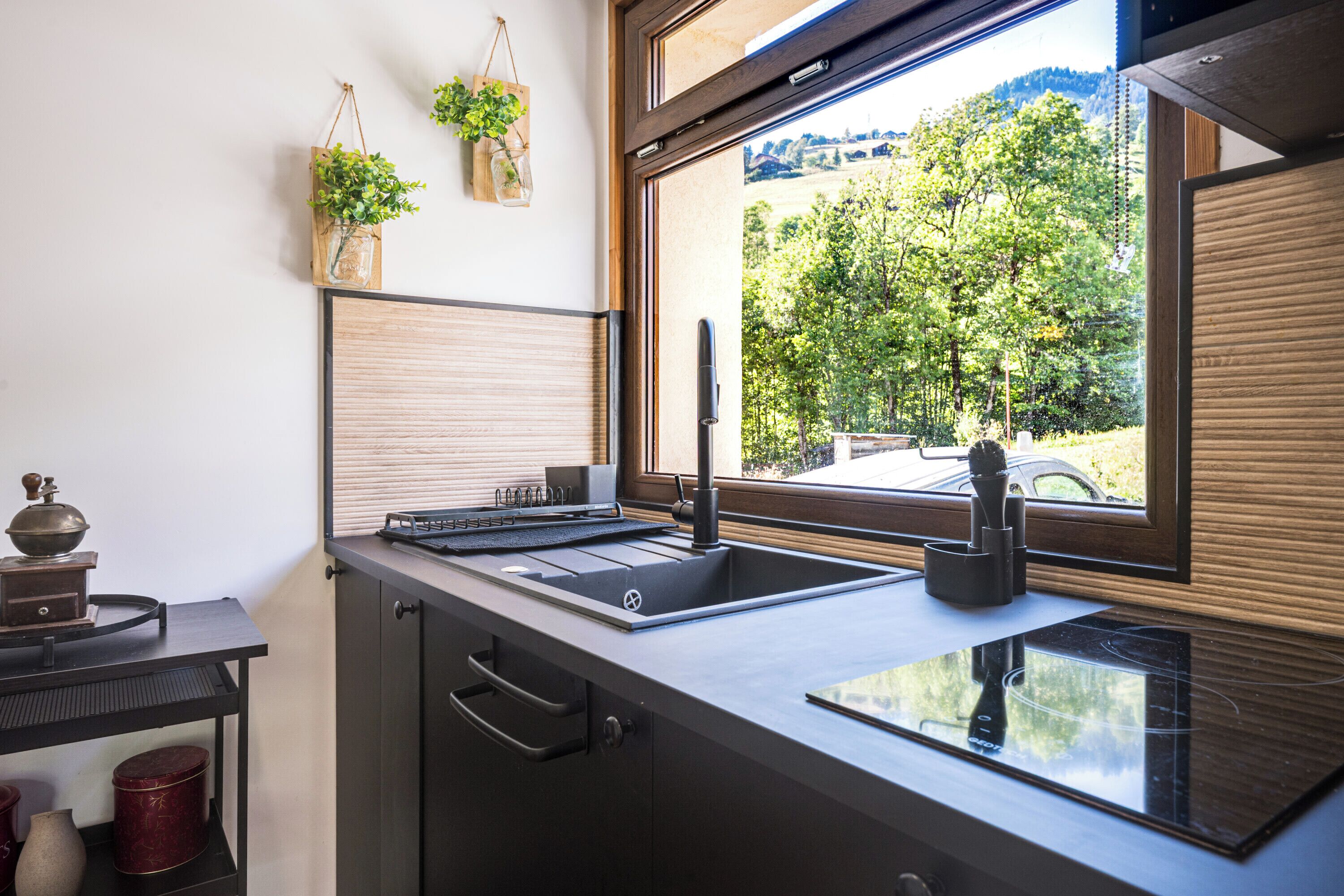 A kitchen with a built-in sink, a wooden countertop, and a window with a view of trees and a car.