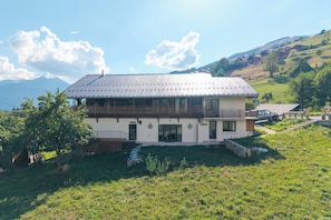 A two-story house with a balcony, a stone pathway leading to the entrance, and a mountainous backdrop. - Le Mont - Petfriendly - Proche pistes (Hauteluce)