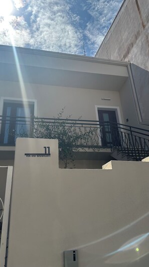 A building with a balcony, a door, and a sign with the number 11. - Domu Fanari Vacation Home in Sardinia (Assemini)