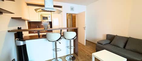 A modern kitchen with a microwave, a stainless steel range hood, and a bar stool area.