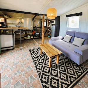 A compact living space with a kitchenette, a sofa, and a patterned rug. - The Kazanbwa with a Sea View (Les Avirons)