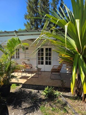 A house with a covered patio, outdoor seating, and a garden with tropical plants. - Vanille House with a Pool (Saint Pierre)