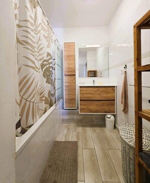Ein Badezimmer mit einem Holzwaschtisch, einem Spiegel und einer Duschkabine.