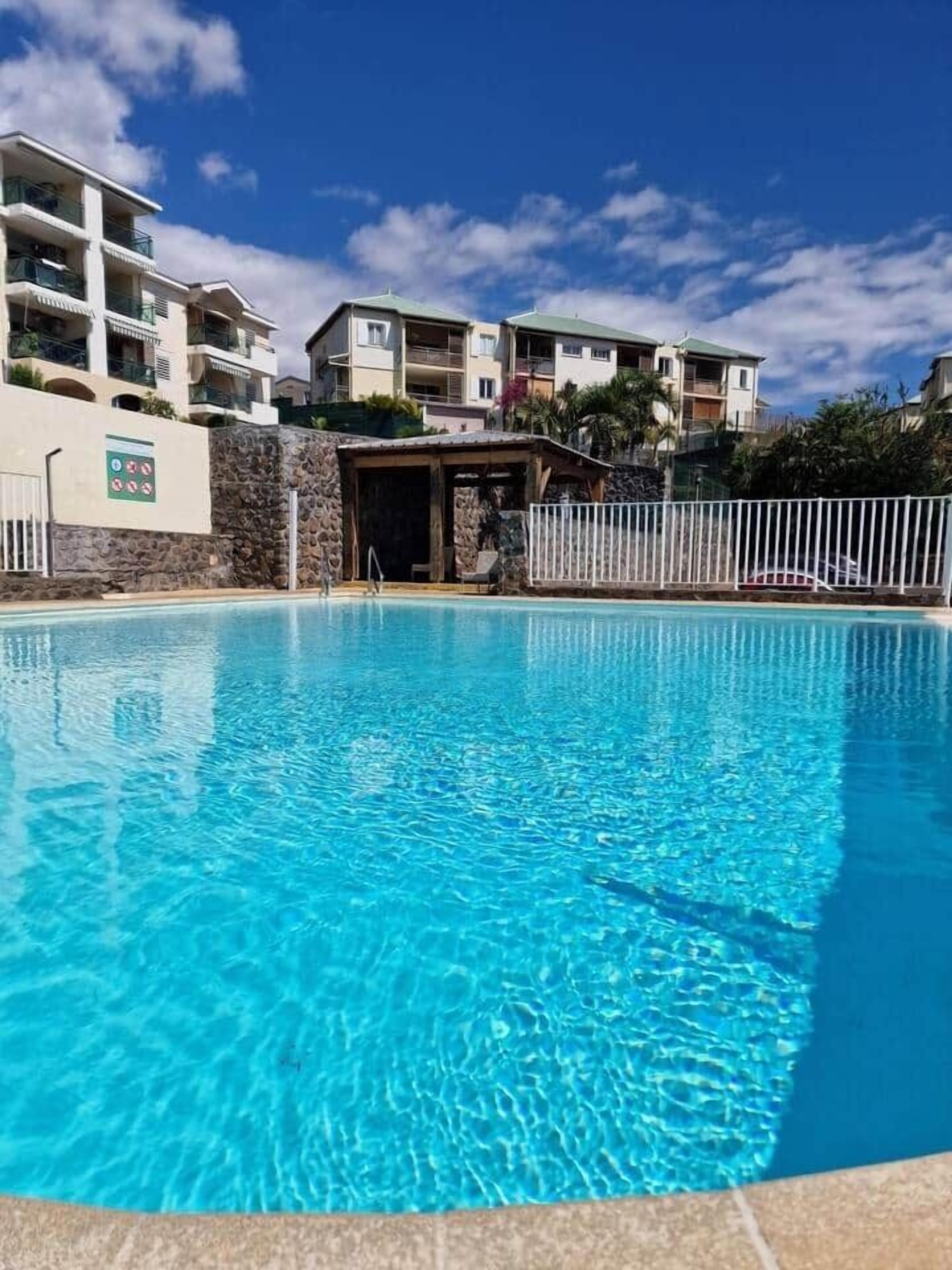 A swimming pool with a stone wall and a white fence.
