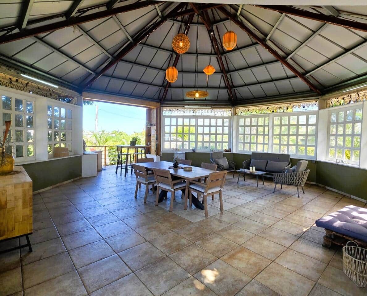 Un patio cubierto con zona de comedor, mobiliario y vistas a la vegetación.