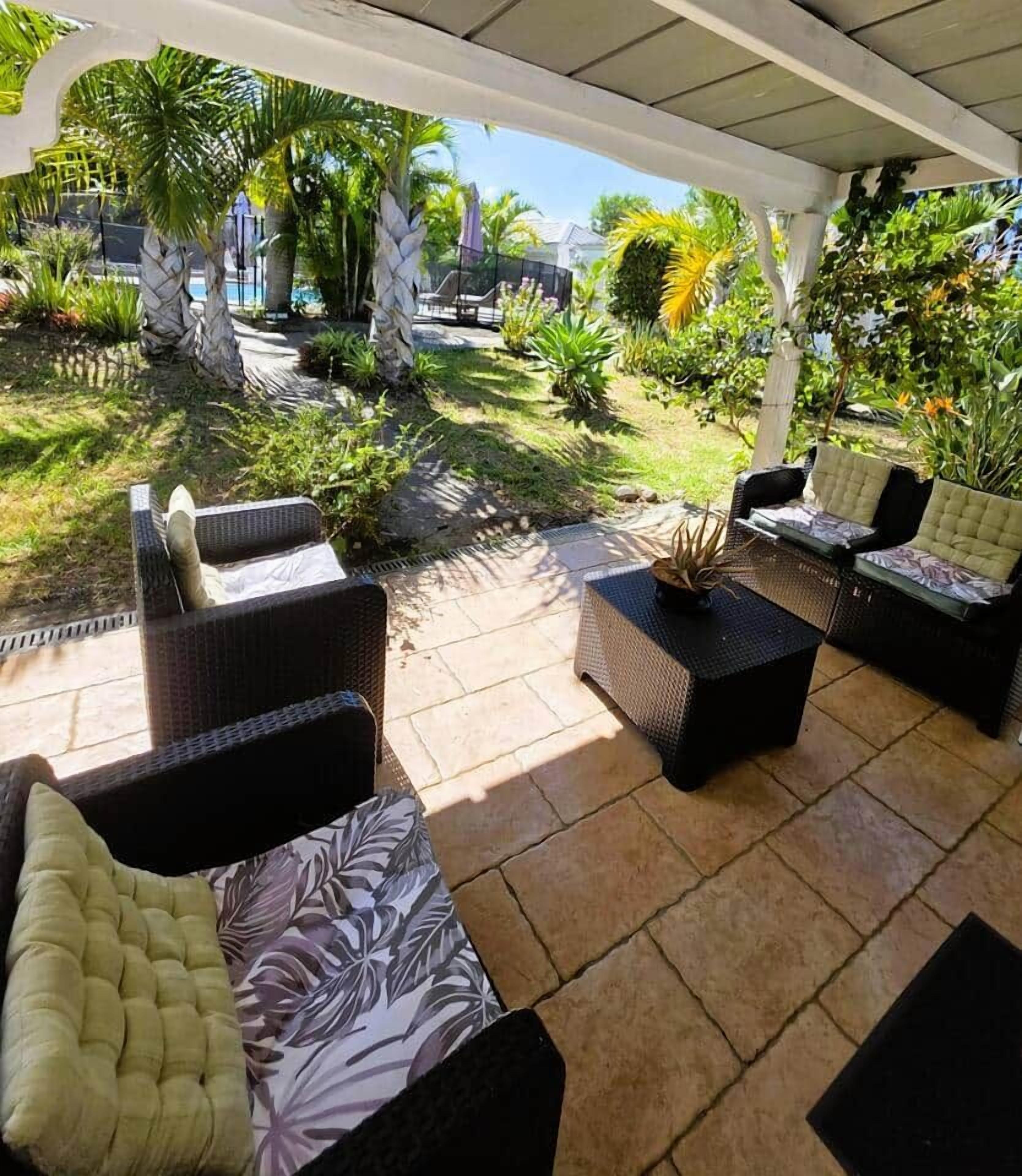 An outdoor patio area with wicker furniture and a covered section.