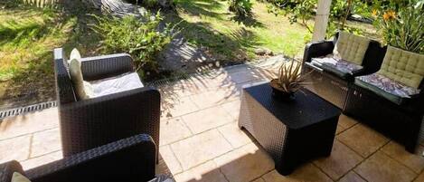 An outdoor patio area with wicker furniture and a covered section.