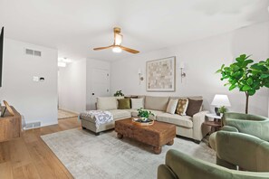 A modern living room with a wooden coffee table, a beige sofa, and a green armchair.