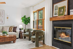 A living room with a fireplace, green chairs, a sofa, and a coffee table.