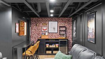 Un espace bar moderne avec un mur en briques, des tabourets de bar, un comptoir avec une caisse enregistreuse et un réfrigérateur rempli de boissons.