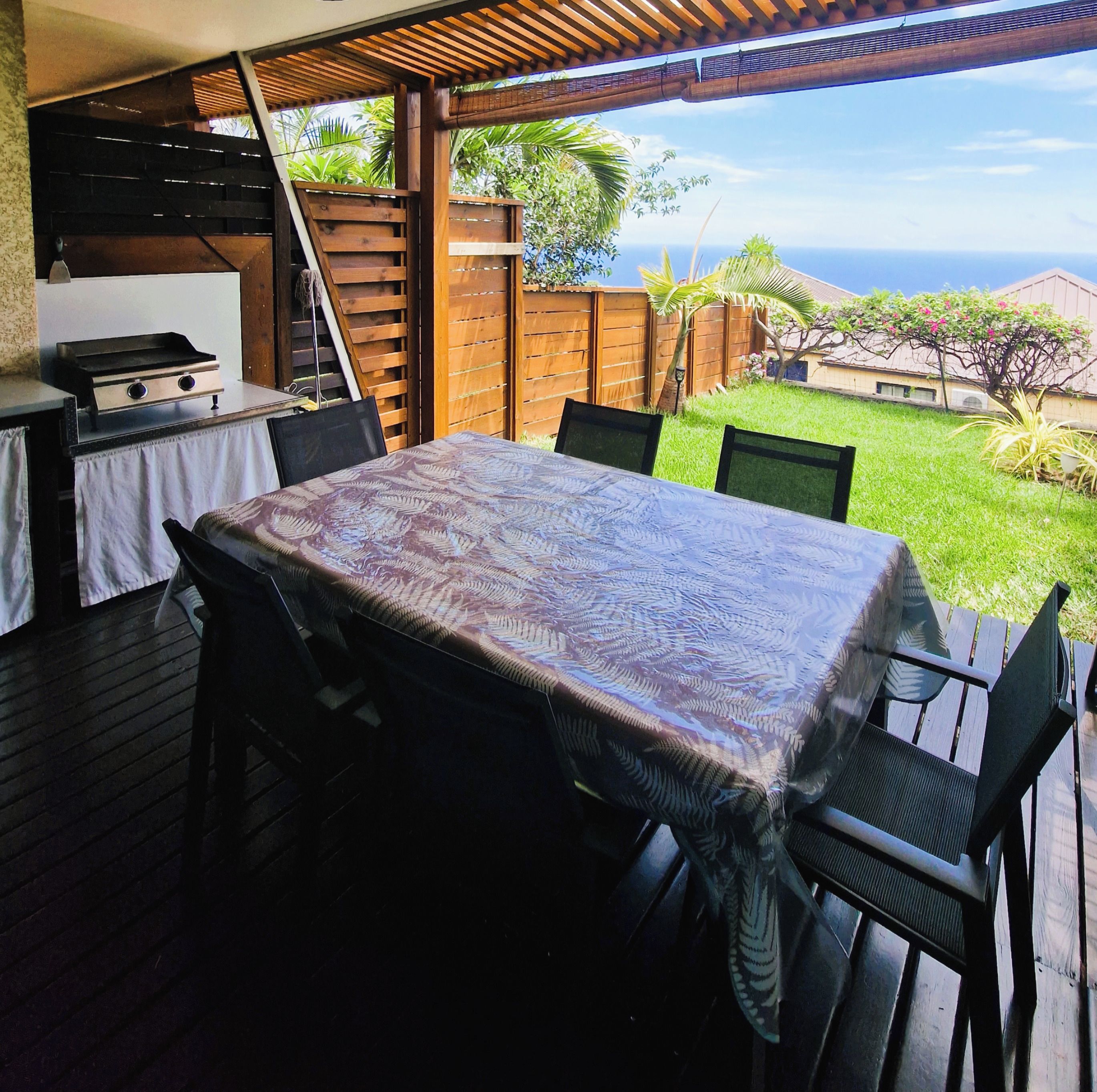 Une terrasse extérieure avec une table et des chaises, un barbecue et une vue sur l’océan.