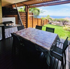 An outdoor patio with a table and chairs, a grill, and a view of the ocean. - Beautiful house in Piton-Saint-Leu, with a view of the sea (Saint-Leu)