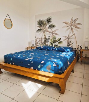 A bedroom with a bed, a mirror, and tropical-themed wallpaper. - Beautiful house in Piton-Saint-Leu, with a view of the sea (Saint-Leu)