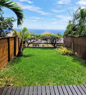 Ein Garten mit einer Holterrasse, einem Rasen und Blick auf den Ozean.
