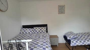 Ein Schlafzimmer mit einem Bett, einem Nachttisch, einer Wanduhr und einem Spruch mit motivierender Botschaft.