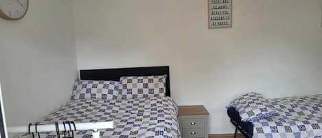 A bedroom with a bed, a bedside table, a wall clock, and a motivational quote sign.