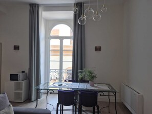A modern dining area with a glass table, two chairs, a potted plant, and a view of a balcony. - NAPLES MARIANA LUXURY: SUPERIOR 2-BEDROOM APARTMENT IN THE CITY CENTER (Napoli)