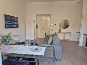 A modern living room with a glass dining table, grey sofa, and a white wardrobe. - NAPLES MARIANA LUXURY: SUPERIOR 2-BEDROOM APARTMENT IN THE CITY CENTER (Napoli)