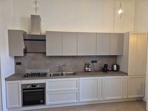 A modern kitchen with a gas stove, oven, sink, and white cabinetry. - NAPLES MARIANA LUXURY: SUPERIOR 2-BEDROOM APARTMENT IN THE CITY CENTER (Napoli)