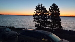 A sunset view with a body of water and trees. - Brand-new oceanfront cottages with unobstructed views of the Atlantic Ocean. (Hubbards)