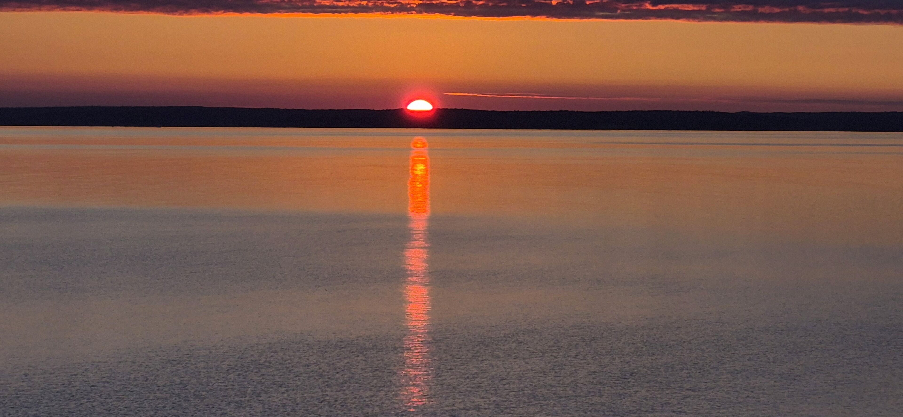 A calm body of water reflecting a sunset.