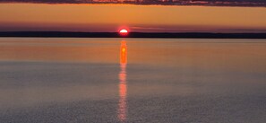 A calm body of water reflecting a sunset. - Brand-new oceanfront cottages with unobstructed views of the Atlantic Ocean. (Hubbards)