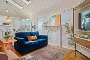 A modern living room with a blue sofa, a fireplace, and a television. - East Austin Studio | Near UT, Downtown & Mueller (Austin)